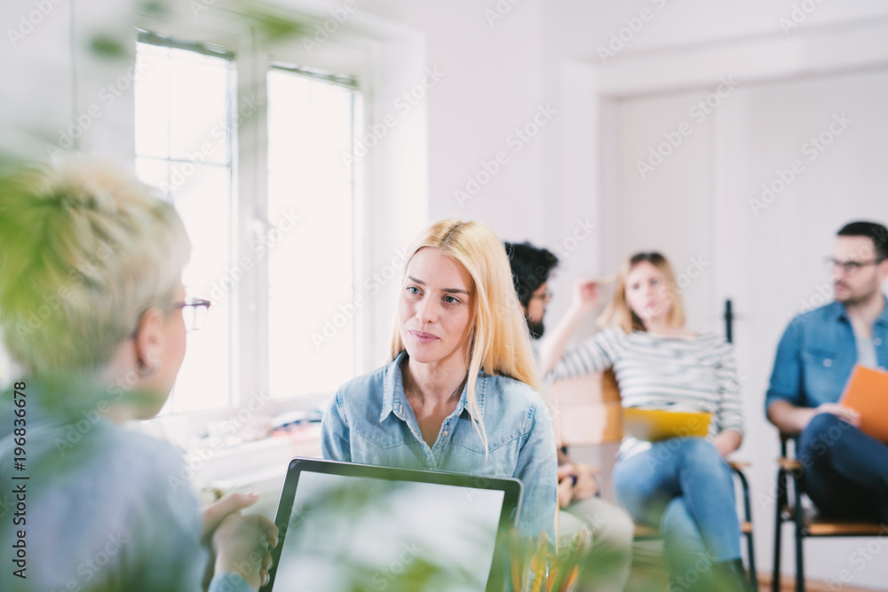 Obraz premium Beautiful young blonde girl speaking with a female boss on the job interview in the large bright office.