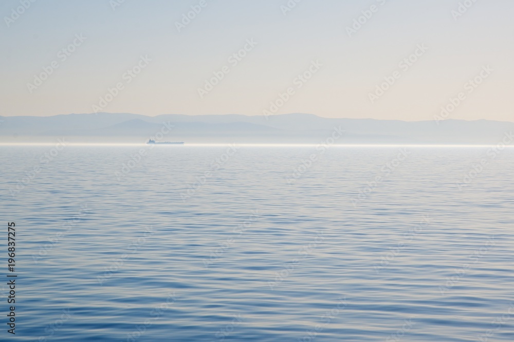 Obraz premium Morning over the Black Sea. Fog on the water. Mountains on the horizon.