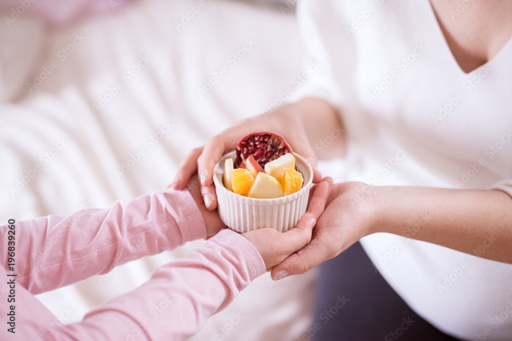 Close up of careful little toddler girl brings fruit salad to her mother. Close up of careful little toddler girl brings fruit salad to her mother.