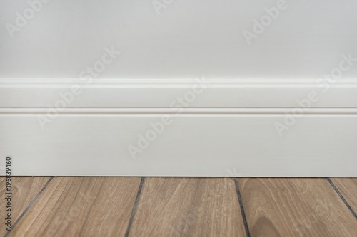 Light matte wall, white baseboard and tiles immitating hardwood flooring photo