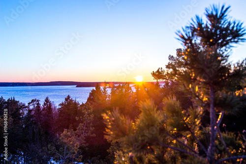 Mountain top bathed in the rays of the sun at sunset overlooking the frozen winter lake from the viewpoint on the mountain top