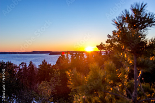 Mountain top bathed in the rays of the sun at sunset overlooking the frozen winter lake from the viewpoint on the mountain top