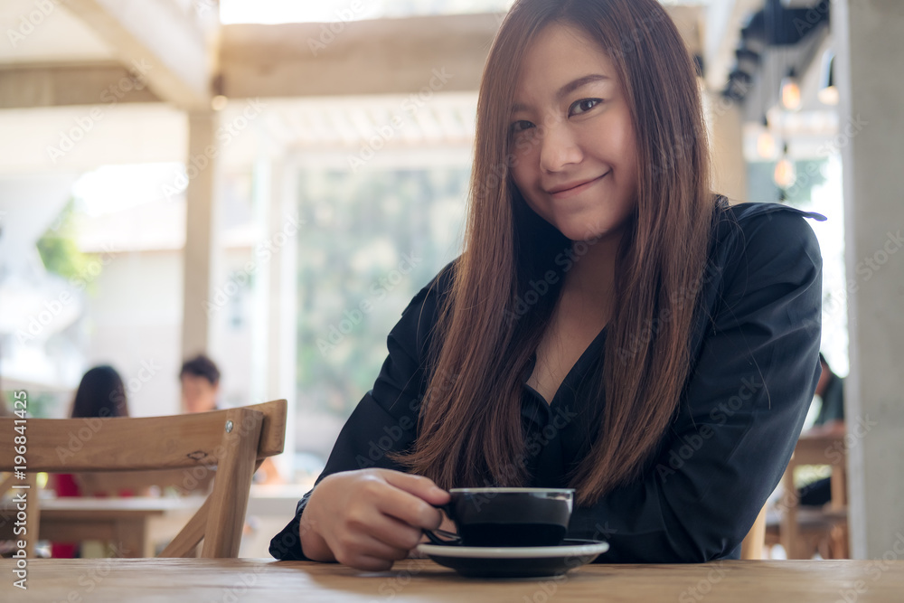 Closeup image of a beautiful asian woman holding and drinking coffee with feeling relaxed in cafe Closeup image of a beautiful asian woman holding and drinking coffee with feeling relaxed in cafe