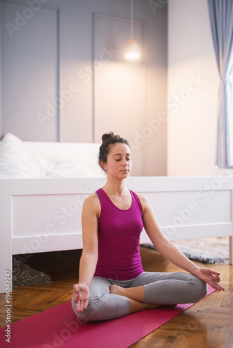 Attractive shape sporty middle aged woman doing seated yoga poses on the floor before sleeping.