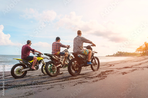 Motorbike race. Three men ride mountain bike on a beach in Bali