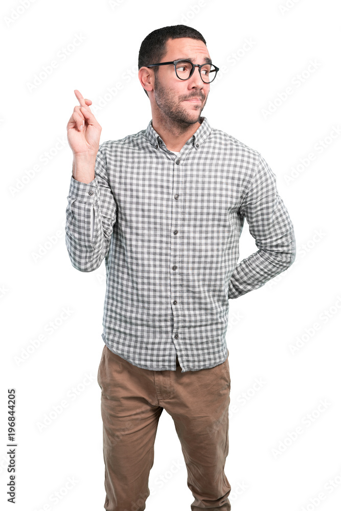 Hopeful young man with finger cross gesture Hopeful young man with finger cross gesture