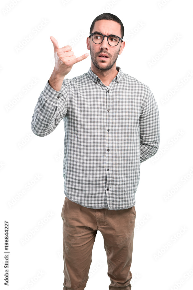Happy young man doing a gesture of call with your telephone Happy young man doing a gesture of call with your telephone