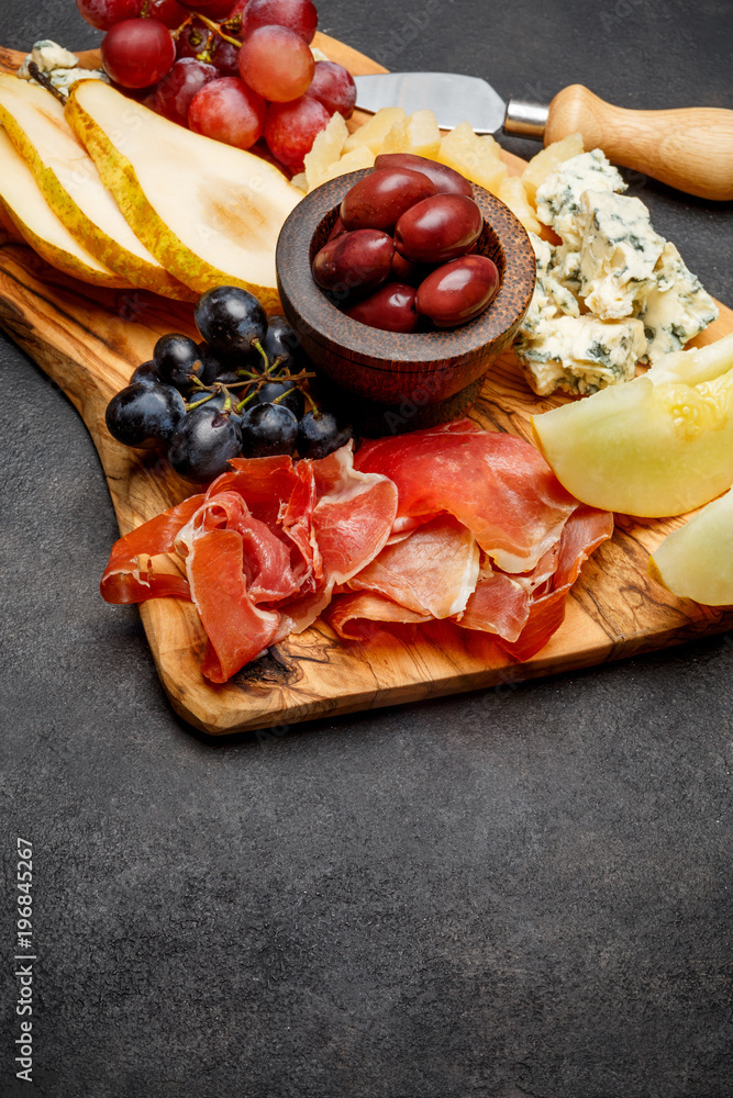 Meat plate antipasti snack - Prosciutto ham, blue cheese, melon, grapes, Olives