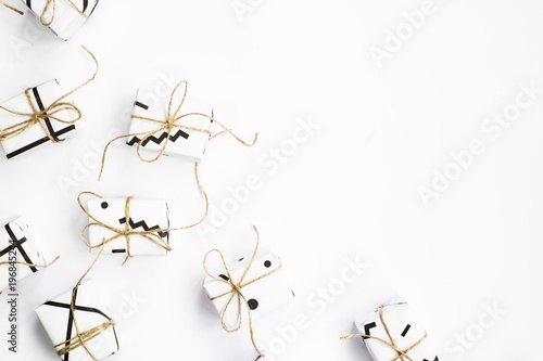 Small gift boxes of white color with black geometric patterns tied with twine. On a white background. Flat lay, Top view, copyspace