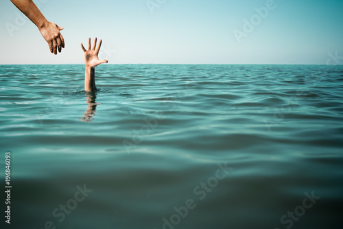 Help hand for drowning man life saving in sea or ocean.
