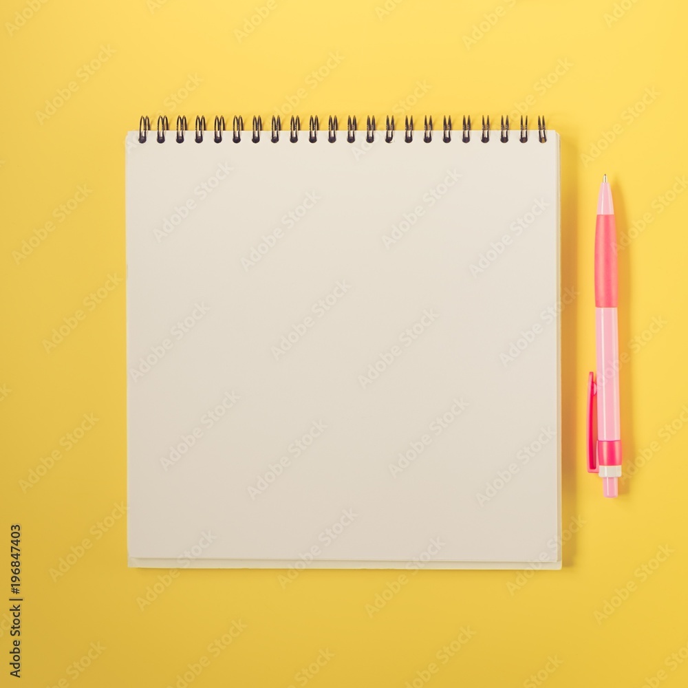 Notebook and pen on yellow background Notebook and pen on yellow background