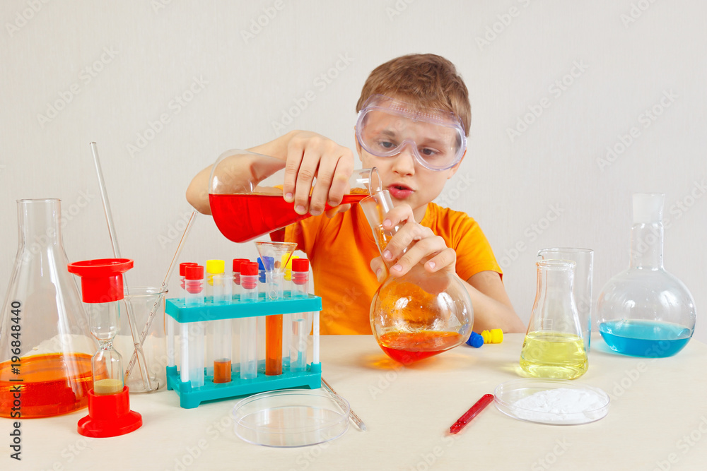 Young smart boy in safety goggles studies chemical practice in the laboratory Young smart boy in safety goggles studies chemical practice in the laboratory