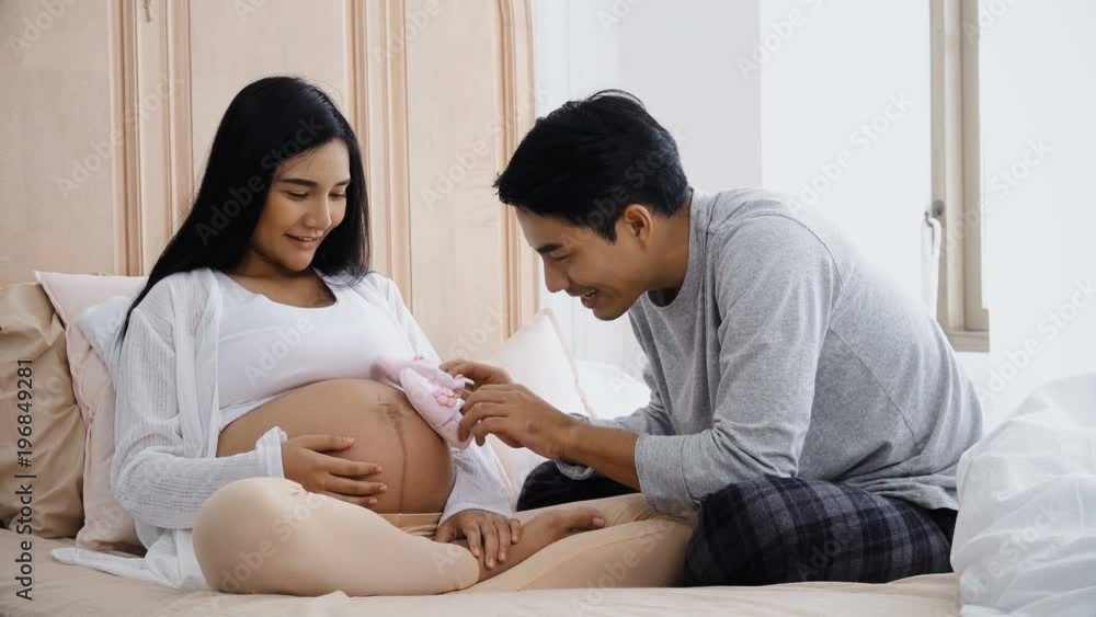 Young husband playing little shoes on belly pregnant wife Young husband playing little shoes on belly pregnant wife
