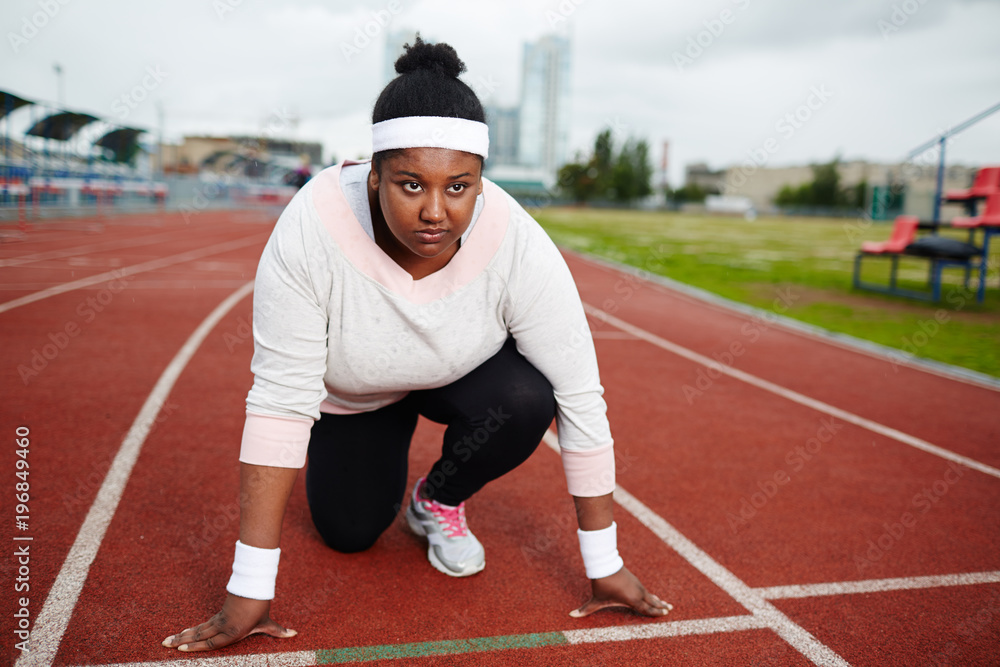 Obraz premium Serious and determined sportswoman looking forwards while standing by start line before marathon