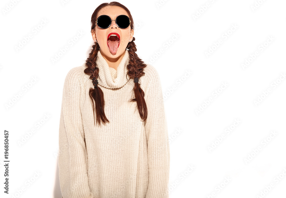 Young happy smiling woman model with bright makeup and red lips with two horns  in summer warm sweater clothes isolated on white. Going crazy and showing her tongue