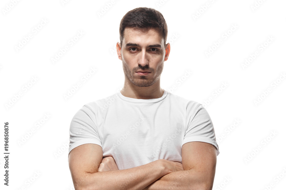 Obraz premium Tough guy standing with crossed arms isolated on white background. Serious young man portrait concept