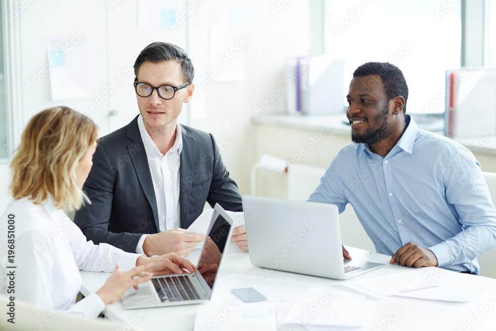 Group of three young economists or analysts organizing working moments at meeting Group of three young economists or analysts organizing working moments at meeting
