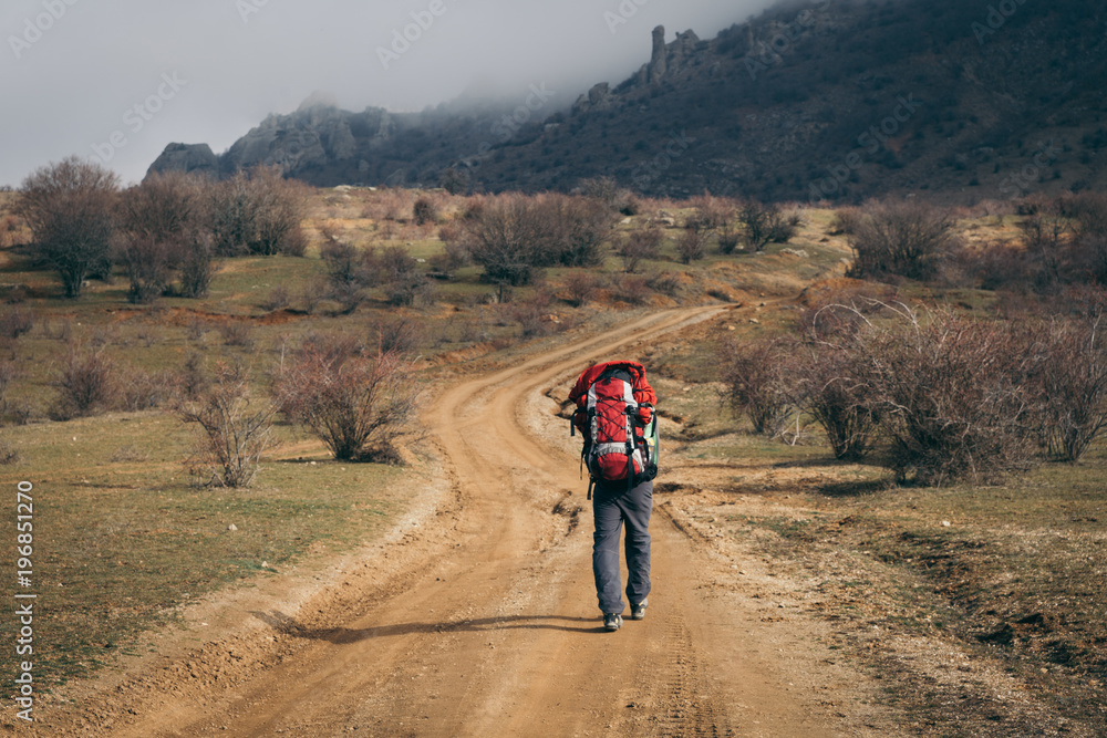 Man backpacks along valley to mist mountain