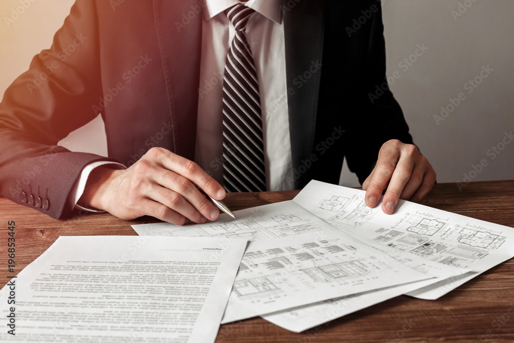 Architect man holding a pen with blueprints for an architectural plan, an engineer sketching a construction project concept. Architect man holding a pen with blueprints for an architectural plan, an engineer sketching a construction project concept.