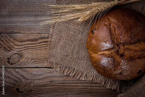  Fresh bread and wheat on burlap at an rustic wood table, top view