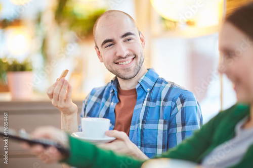 Happy man drinking tea with his girlfriend while watching TV