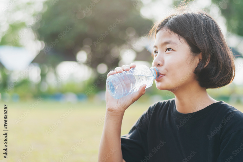 asian little girl drinking fresh water from plastic bottle with sunset background asian little girl drinking fresh water from plastic bottle with sunset background