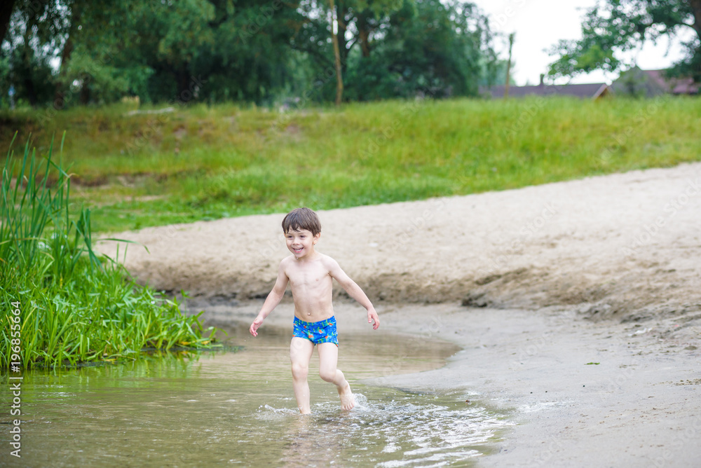 Happy little boy having fun and running in water in the river at summer day time, summertime lifestyle outdoor, friendly family weekend concept, healthy active lifestyle Happy little boy having fun and running in water in the river at summer day time, summertime lifestyle outdoor, friendly family weekend concept, healthy active lifestyle