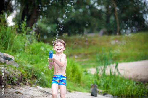 Fototapeta Naklejka Na Ścianę i Meble -  Portrait of caucasian little boy in straw hat playing toys and water pump on the beach.
