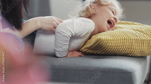 Close up hand mother having fun with her kid daughter tickling on sofa home woman baby love child girl young cheerful little beautiful happy joy smile childhood cute together laugh lying activities