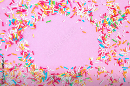Multicolored confetti on a pink background top view