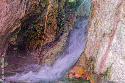 Small waterfall near a hot spring in Main, with colored precipitates of iron, copper, manganese and sulfur compounds