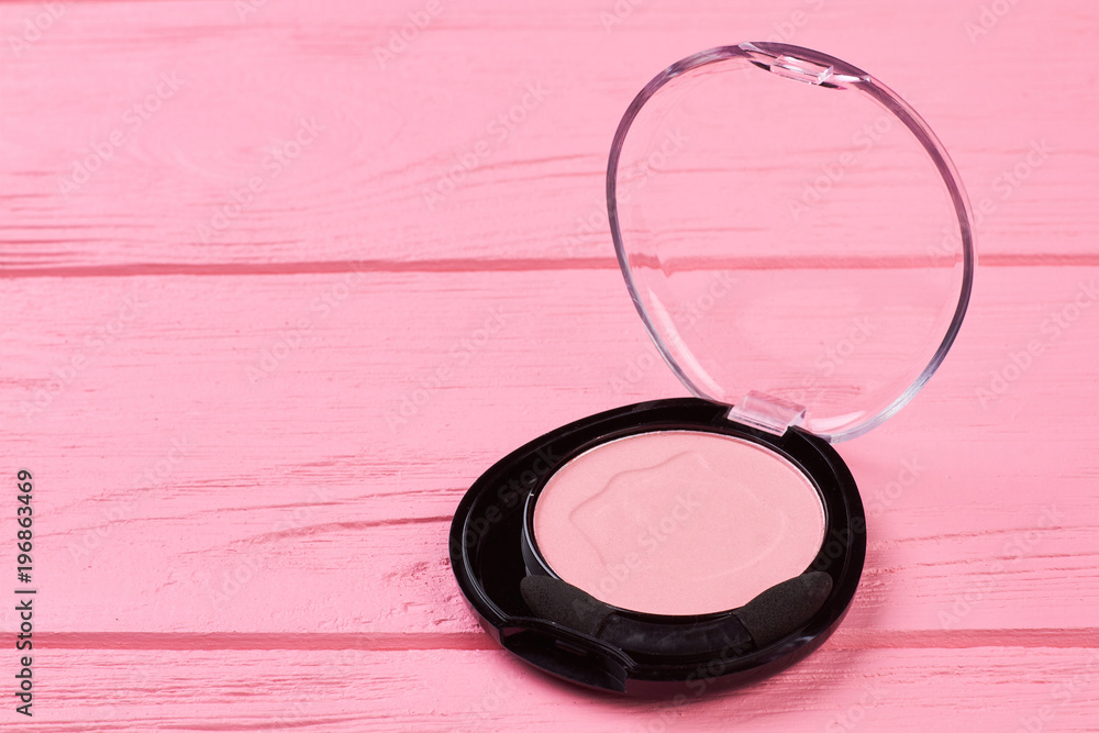Pink face blusher on pink wooden background. Round pink blusher for make up. Cosmetic product on colorful wooden background. Pink face blusher on pink wooden background. Round pink blusher for make up. Cosmetic product on colorful wooden background.