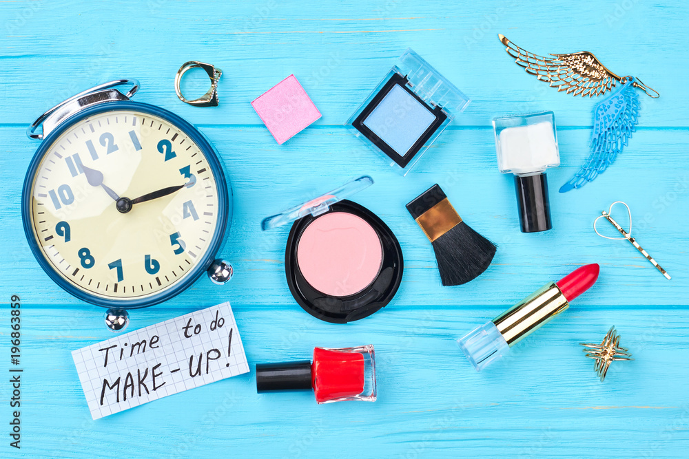 Flat lay cosmetics and alarm clock. Cosmetics, makeup tools and mechanical alarm clock on wooden background. Time to do makeup. Flat lay cosmetics and alarm clock. Cosmetics, makeup tools and mechanical alarm clock on wooden background. Time to do makeup.