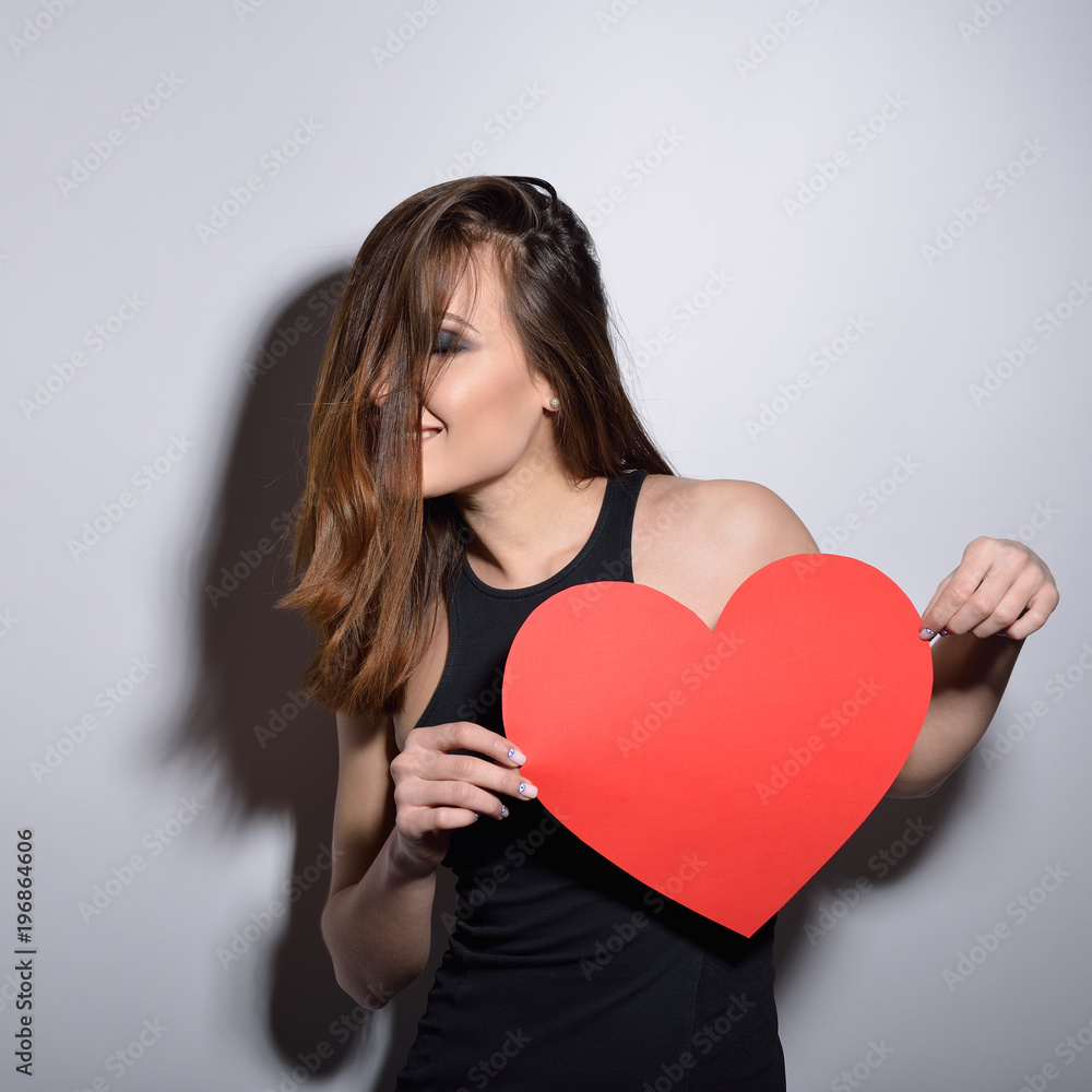 Heartbreaker. Temptress. Seductive woman. Portrait of amazing young fashion woman posing at studio with red heart. Love. Valentine's day. Heartbreaker. Temptress. Seductive woman. Portrait of amazing young fashion woman posing at studio with red heart. Love. Valentine's day.