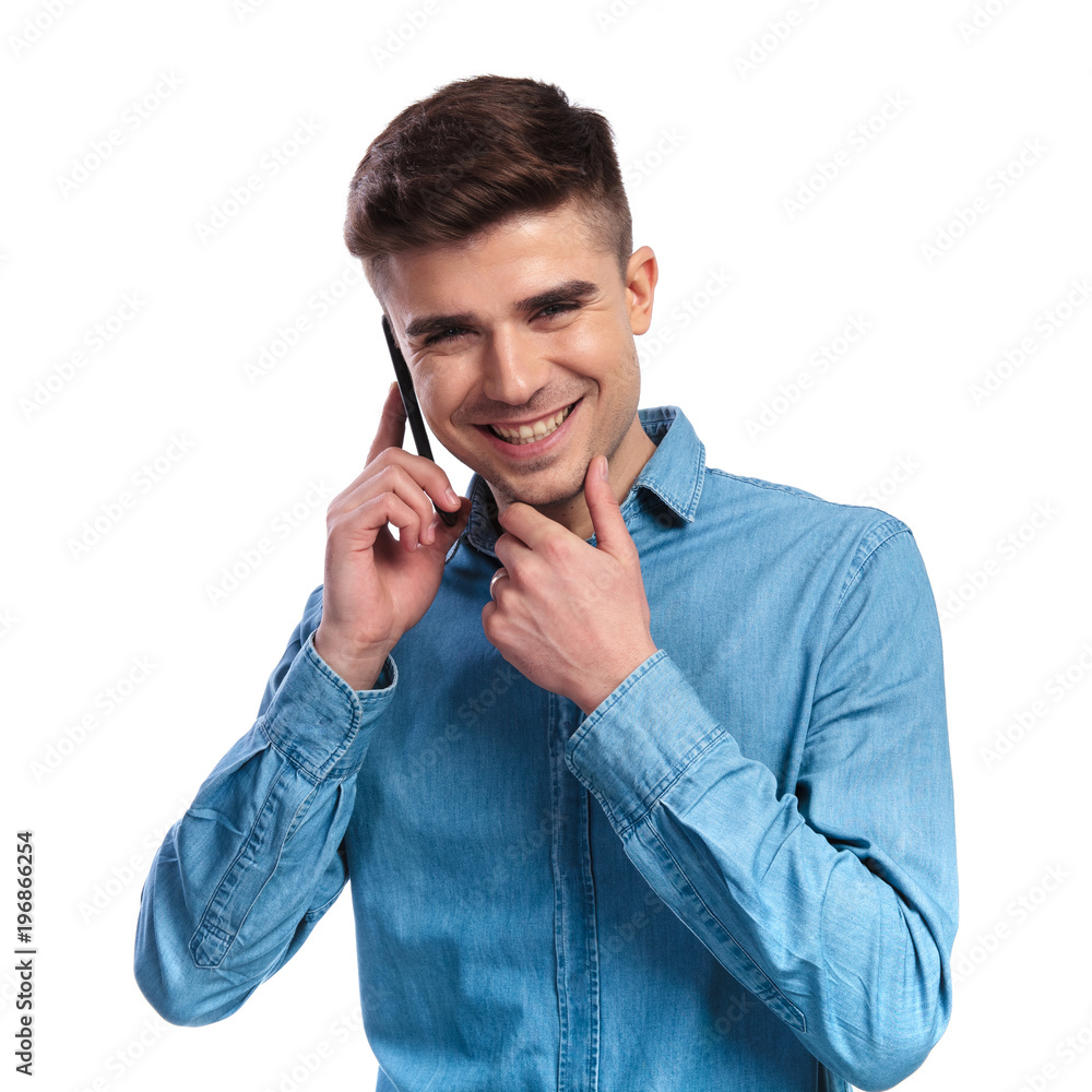 smiling casual man talking on the phone is thinking smiling casual man talking on the phone is thinking