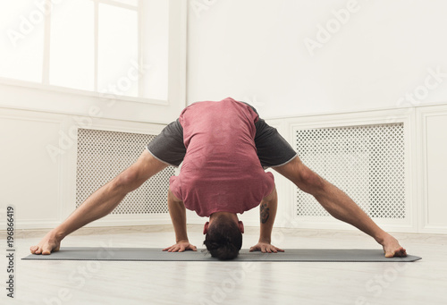 Young flexible man standing on hands