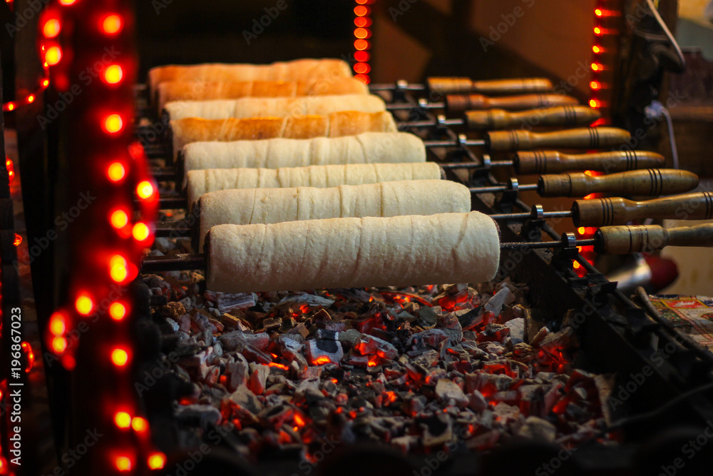 Fototapeta premium Kurtos kalacs (Chimney Cakes) baking on roll spinning over hot coals at a Christmas market stand