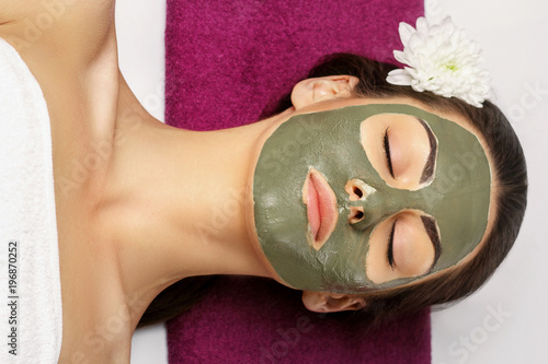 Woman with clay facial mask in beauty spa. Skincare. Beauty Co