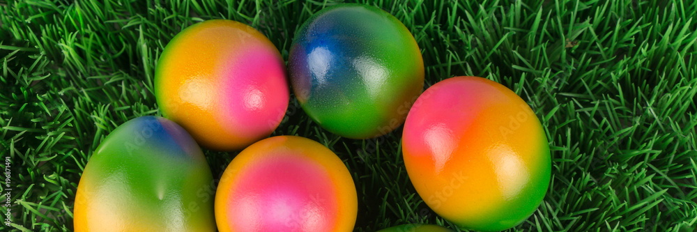 Colorful Easter eggs in grass, banner, view from above Colorful Easter eggs in grass, banner, view from above