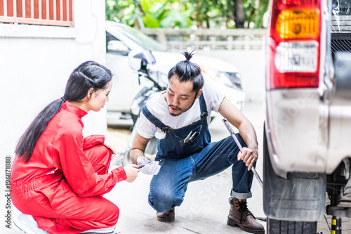 Fixing car engine in automobile repair garage. Handsome mechanics in uniform are repairing car while working in auto service