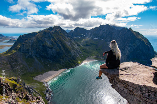 Obraz na plátně Adventurous woman looking down at Kvalvika Beach in Lofoten, Norway
