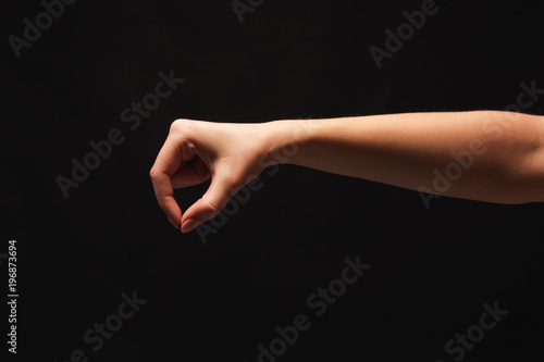 Female hand picking up something, cutout at black