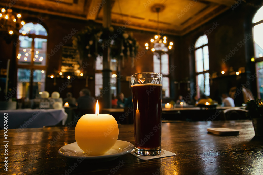 Vue d'une bougie et d'une pinte de bière brune sur une table d'une brasserie
