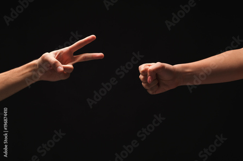Two hands playing rock paper scissors on black background