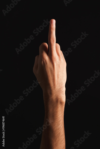 Man showing middle finger at black background