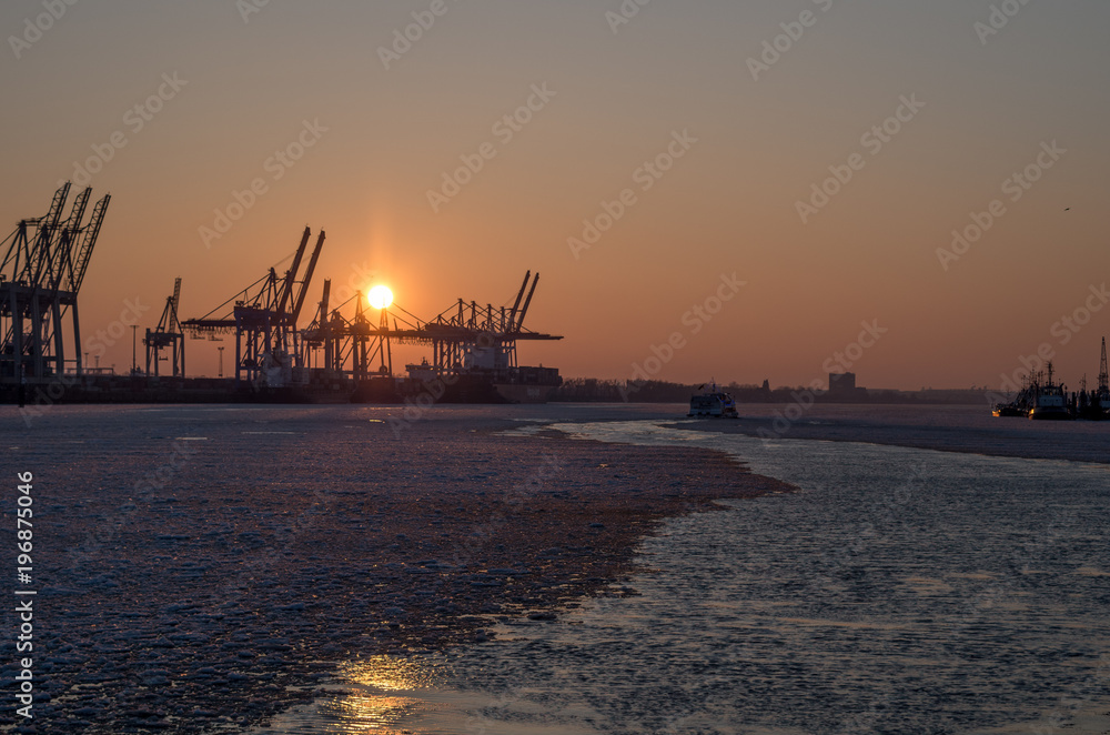 Hamburger Hafen mit Eis auf der Elbe und Sonnenuntergang