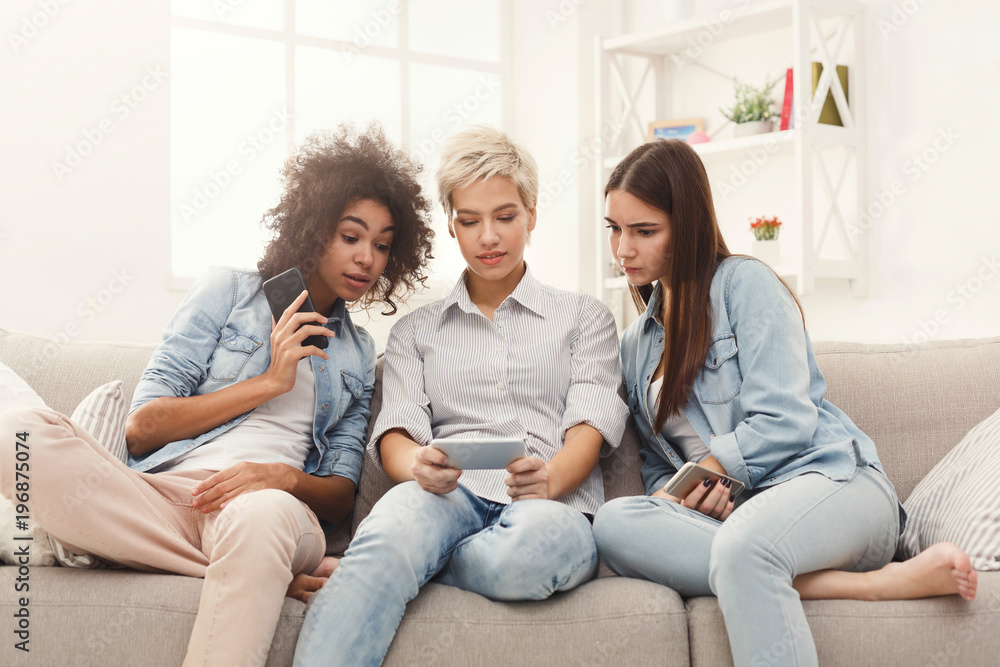 Three female friends using smartphones at home Three female friends using smartphones at home
