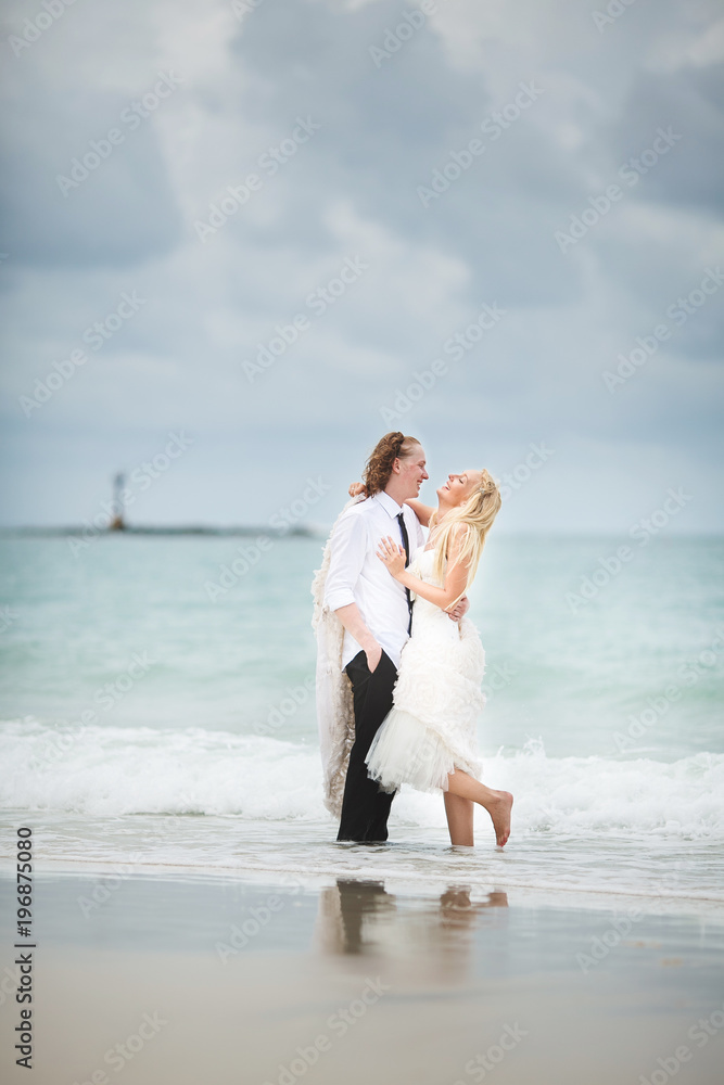 bride in wedding dress and groom hugging at the sea. couple love on deserted beach.