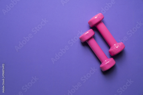 two pink dumbbell on purple background, sport and healthy concept