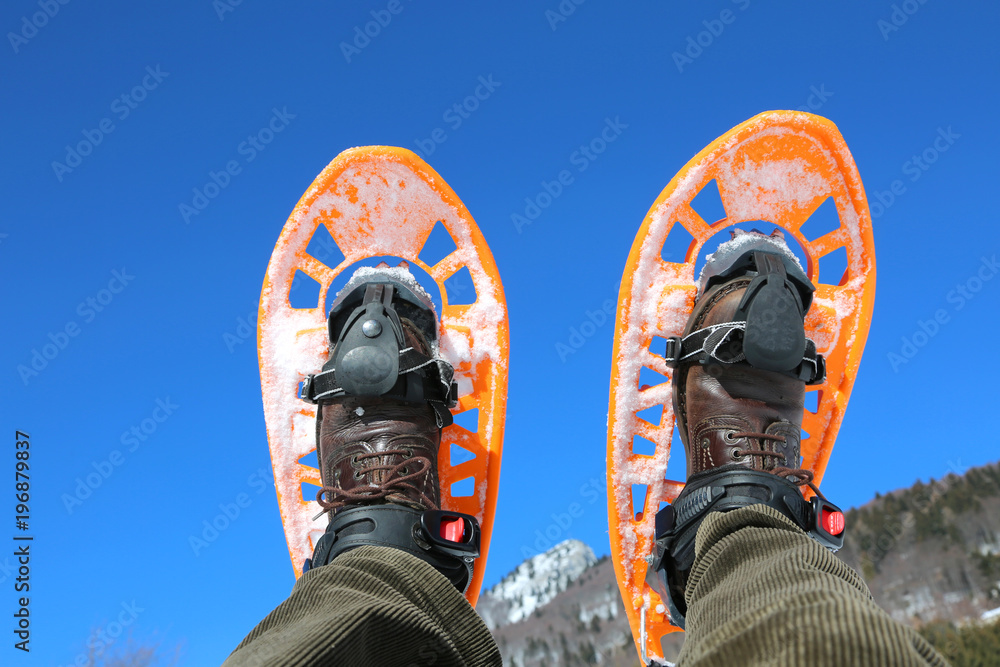 man in mountains with orange snowshoes man in mountains with orange snowshoes